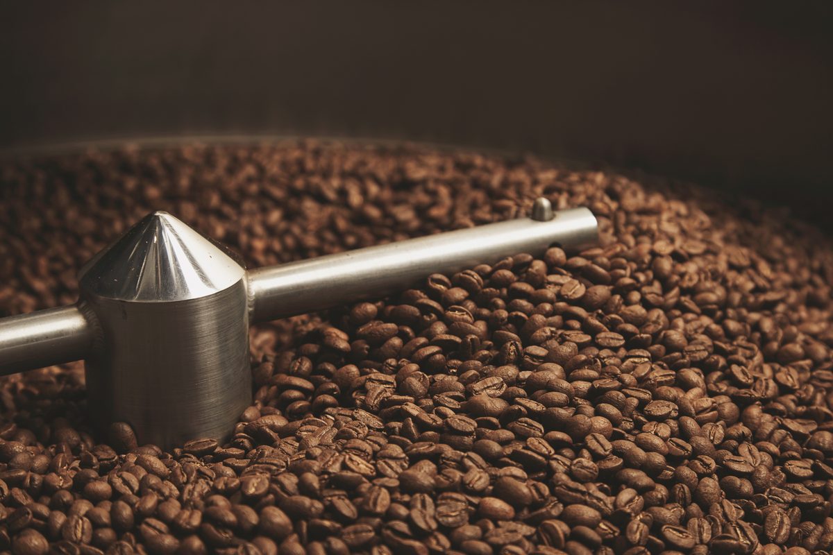 Taza de espresso blanca sobre mármol claro con granos de café verde descafeinado esparcidos alrededor, luz natural suave